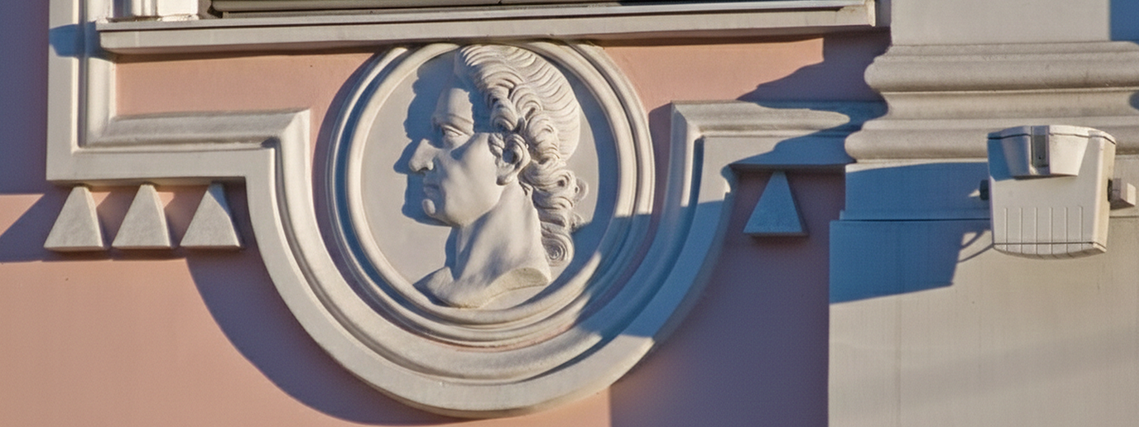 Барельеф на фасаде Строгановского дворца: декоративные медальоны с мужским профилем под окнами и детали барокко
